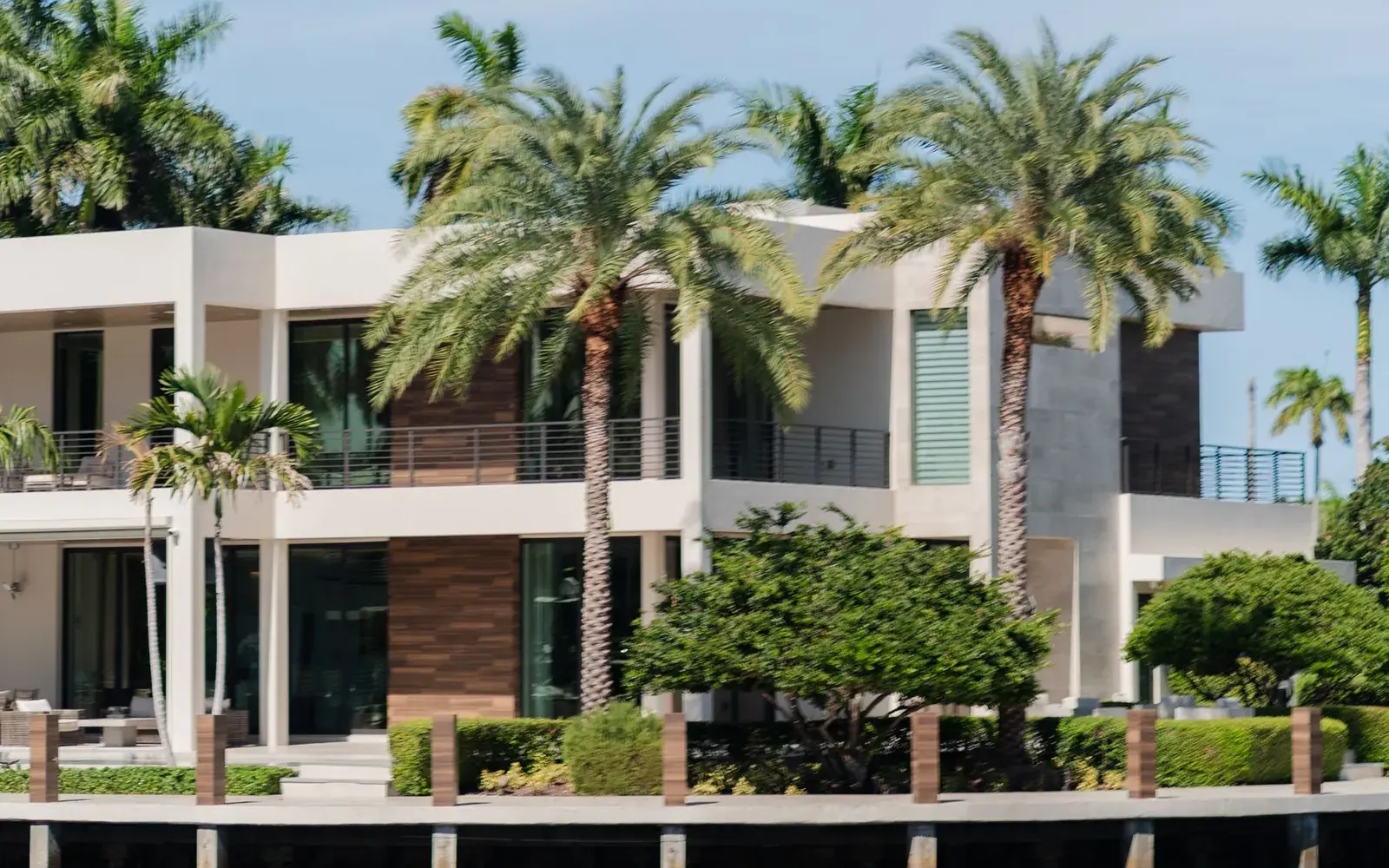 Casa moderna frente al agua con palmeras junto a un canal tranquilo